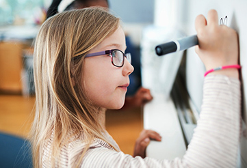 Young girl in classroom who is covered through the ACA pediatric vision provision