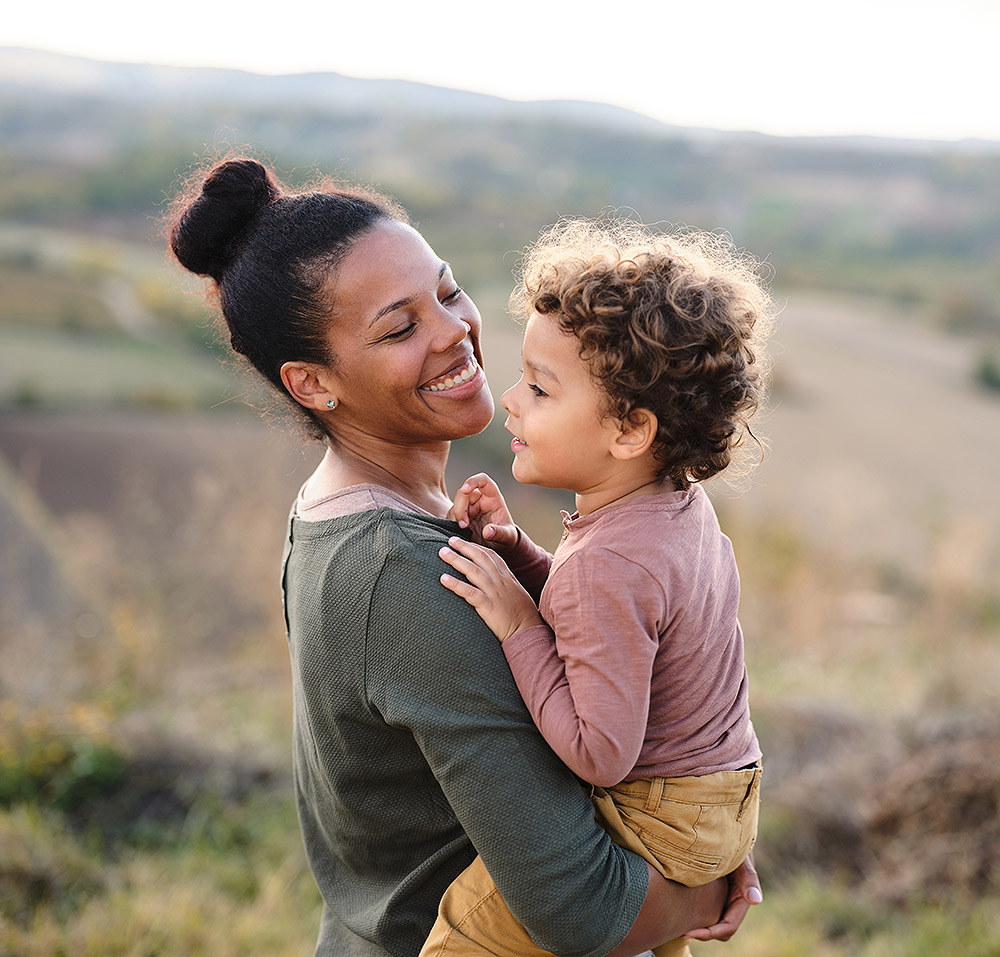 Madre sonriente e hija pequeña en una caminata