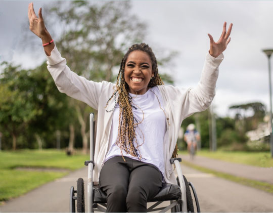 Happy smiling lady in a wheelchair enjoying the outdoors