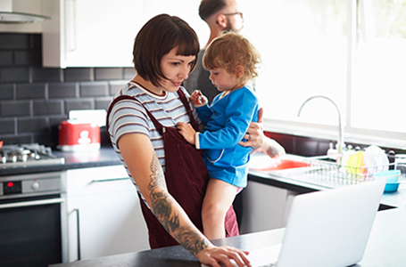 woman holding child while on laptop