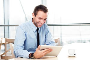 Man smiling while reading a tablet